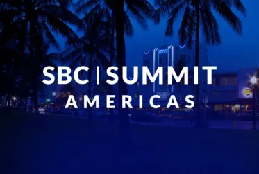 SBC Summit Americas logo on a blue-tinted city scene with palm trees at dusk.