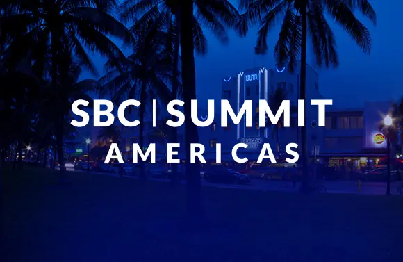 SBC Summit Americas logo on a blue-tinted city scene with palm trees at dusk.